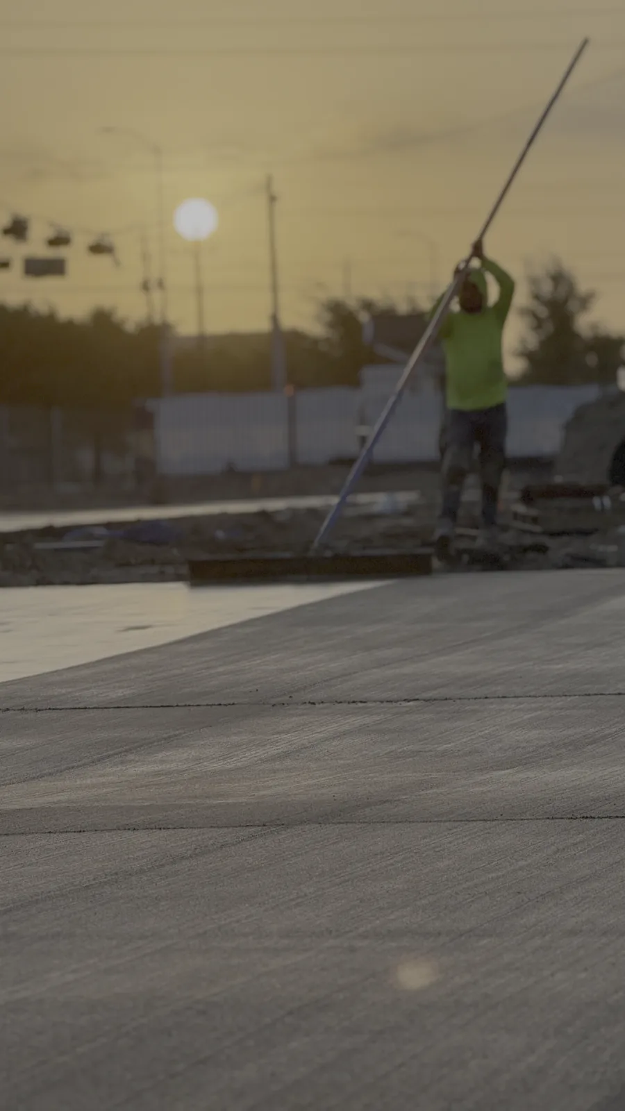 Crew member screeding a concrete slab at sunset on a Texas commercial project