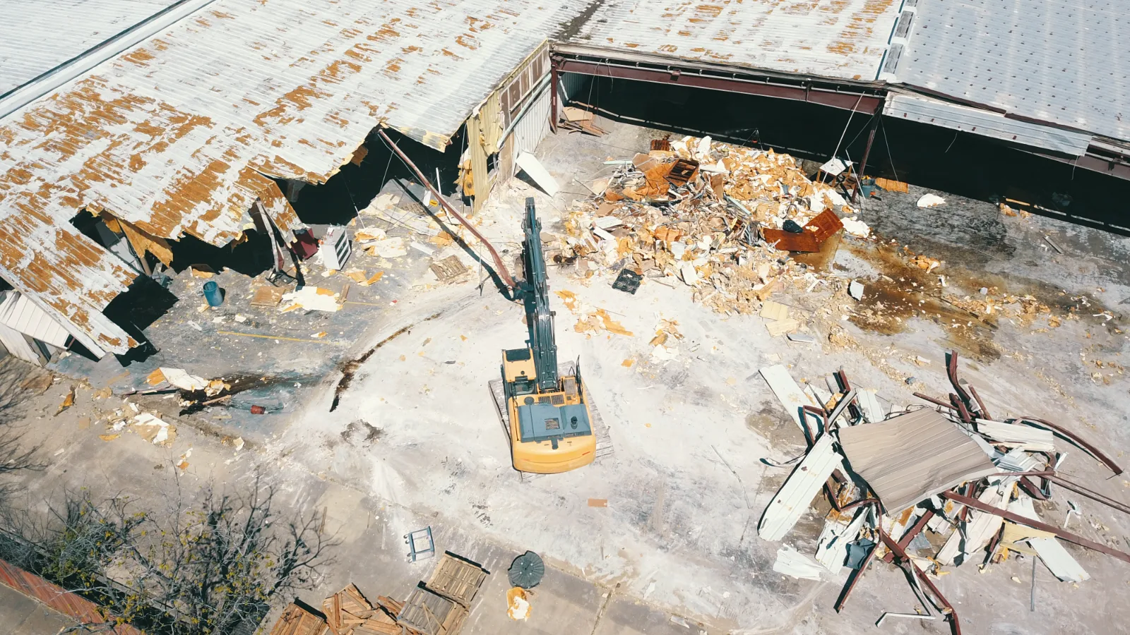 Excavator demolishing an existing metal building on a Houston commercial site